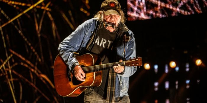 neil young performing on stage before tour cancellation